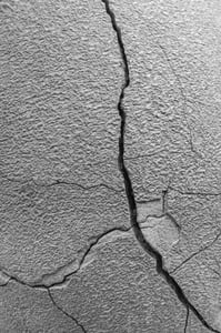 Garden abstract in black and white Closeup of long crack, with tributaries, in the side of a large planter, for concepts of time, pressure, susceptibility, or imperfection